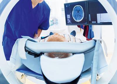 Krankenpfleger begleitet Patient während dieser in einen Kernspin kommt.